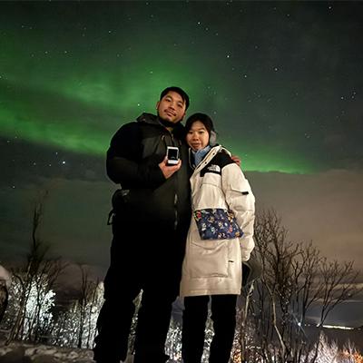 Couple engagement with diamond ring under northern lights